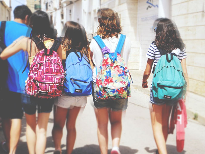 Grupo de cuatro chicas adolescentes con mochilas Eastpak